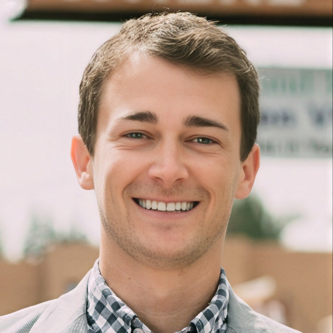 Headshot of George Stern, leadership keynote speaker, smiling at the camera in a checked collared shirt.